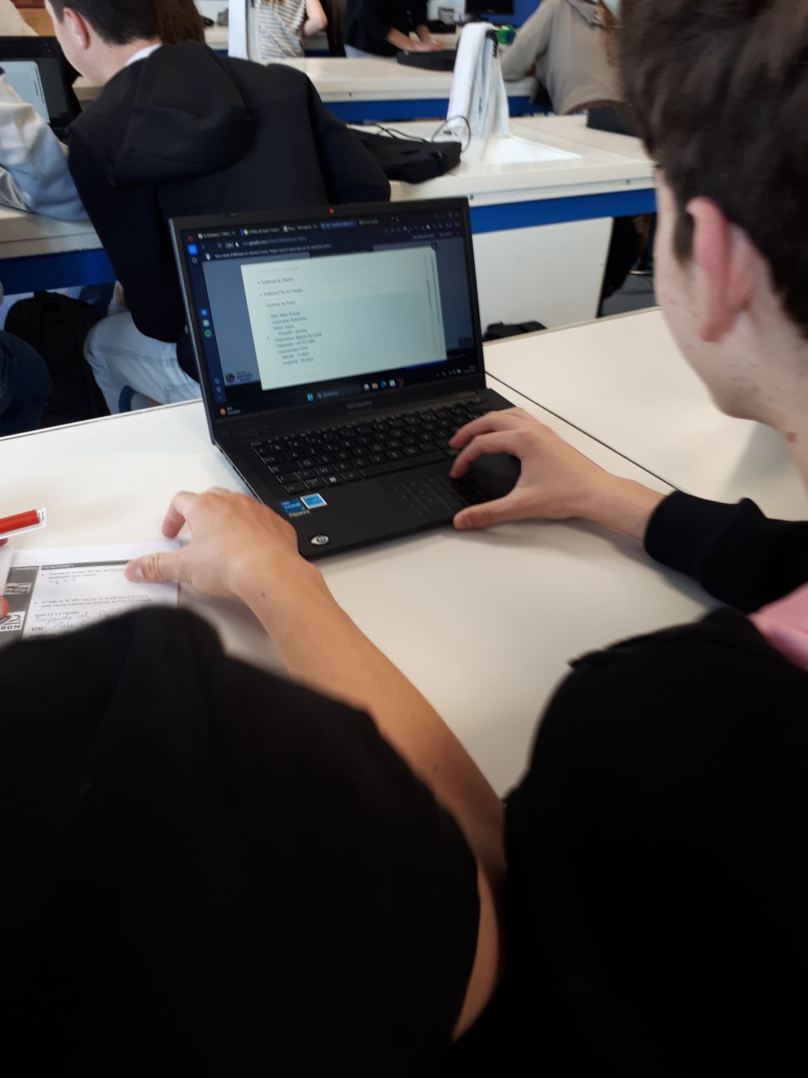 Eleves de dos dans une salle de classe, devant leurs ordinateurs