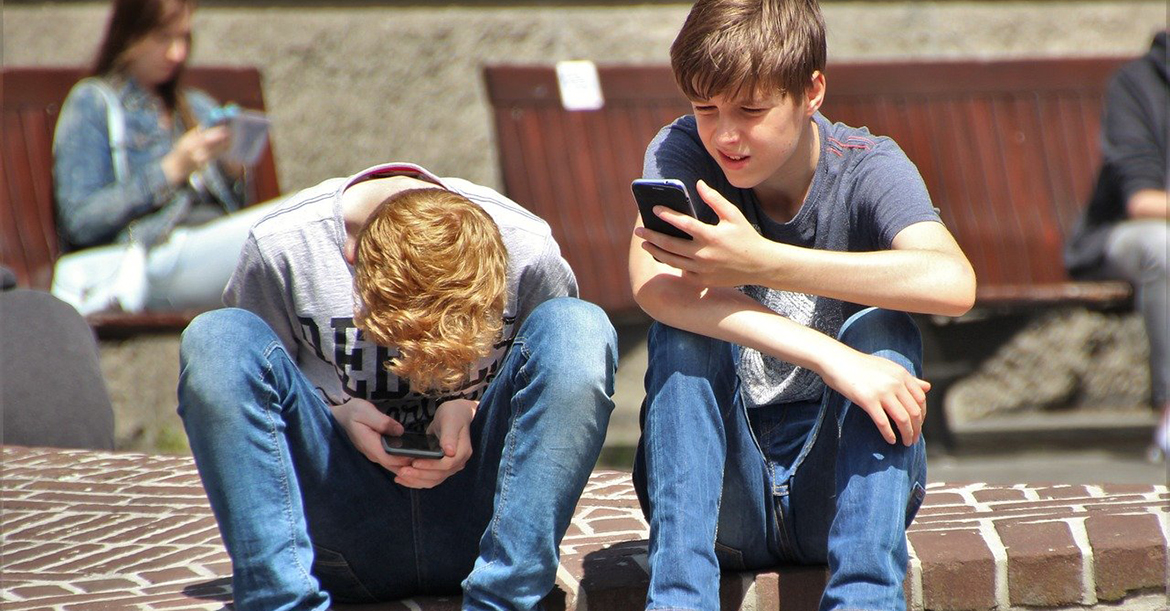 Photo de deux garçons adolescents sur leur téléphone portable